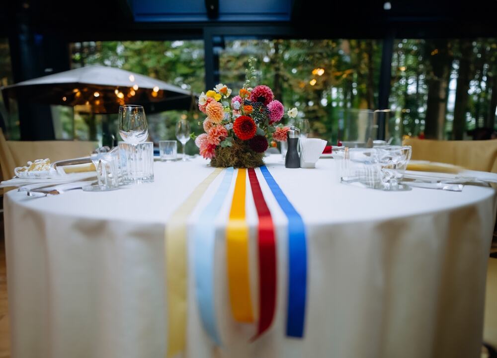 A table with linens, floral centerpiece, and colorful ribbon runners