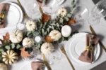 An elegant Thanksgiving table with a white tablecloth and brown linen napkins