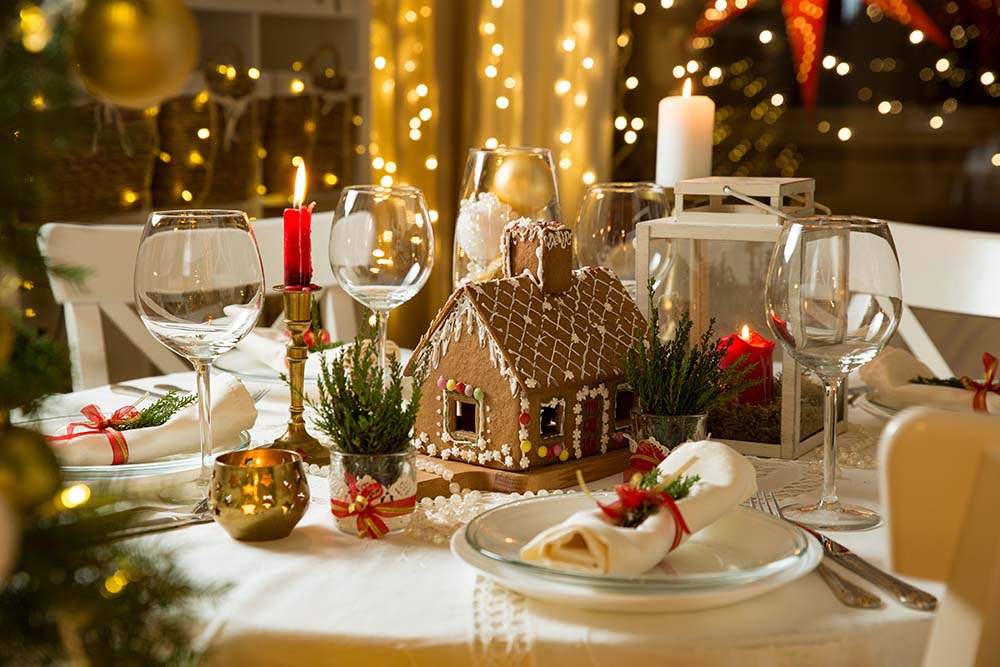 A table decorated for a Christmas party with a gingerbread house centerpiece