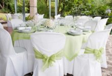 A beautiful table setting at a wedding with green sashes on the chairs