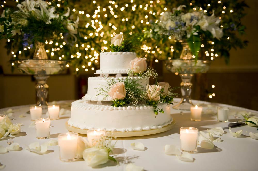 A wedding cake table with candles and lights