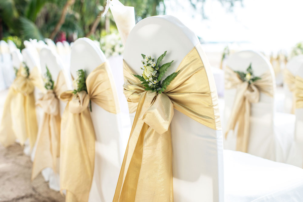 Chairs at a wedding with gold sash bows