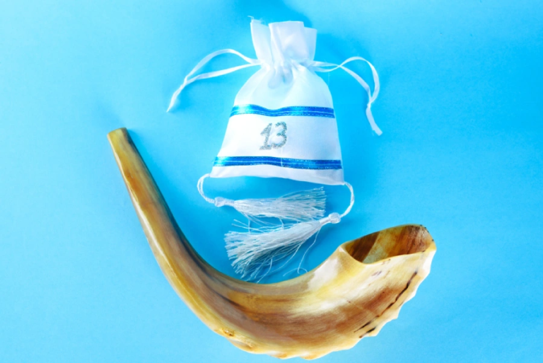 A shofar and bar mitzvah gift bag on a bright blue background