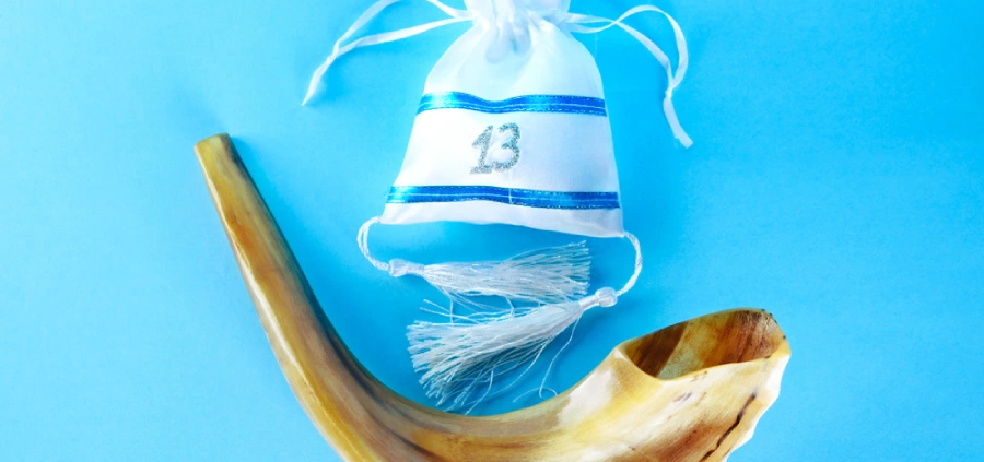 A shofar and bar mitzvah gift bag on a bright blue background